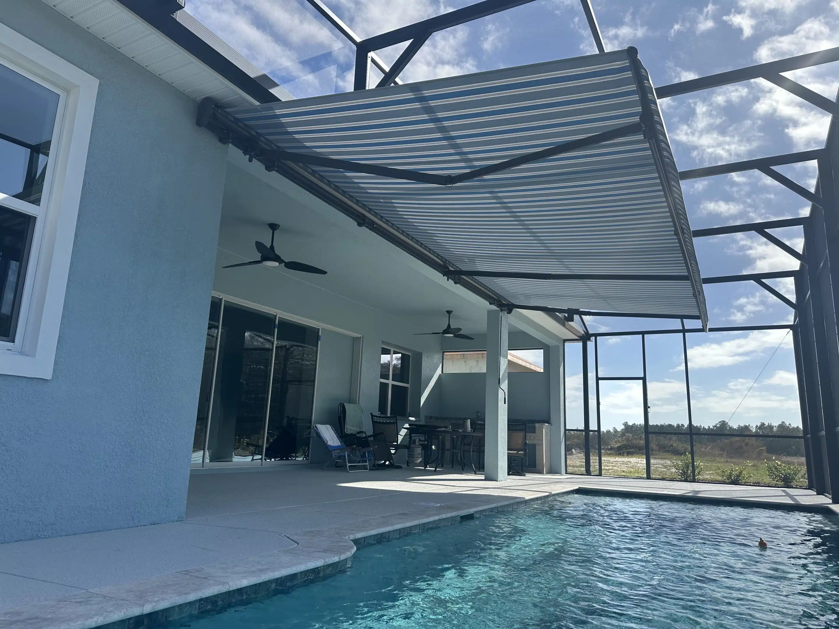 Homeowner enjoying comfortable outdoor space under motorized awning during Florida peak sun hours